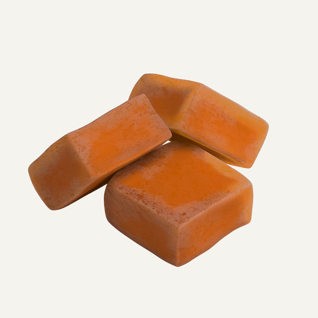 Three orange caramels on a white background